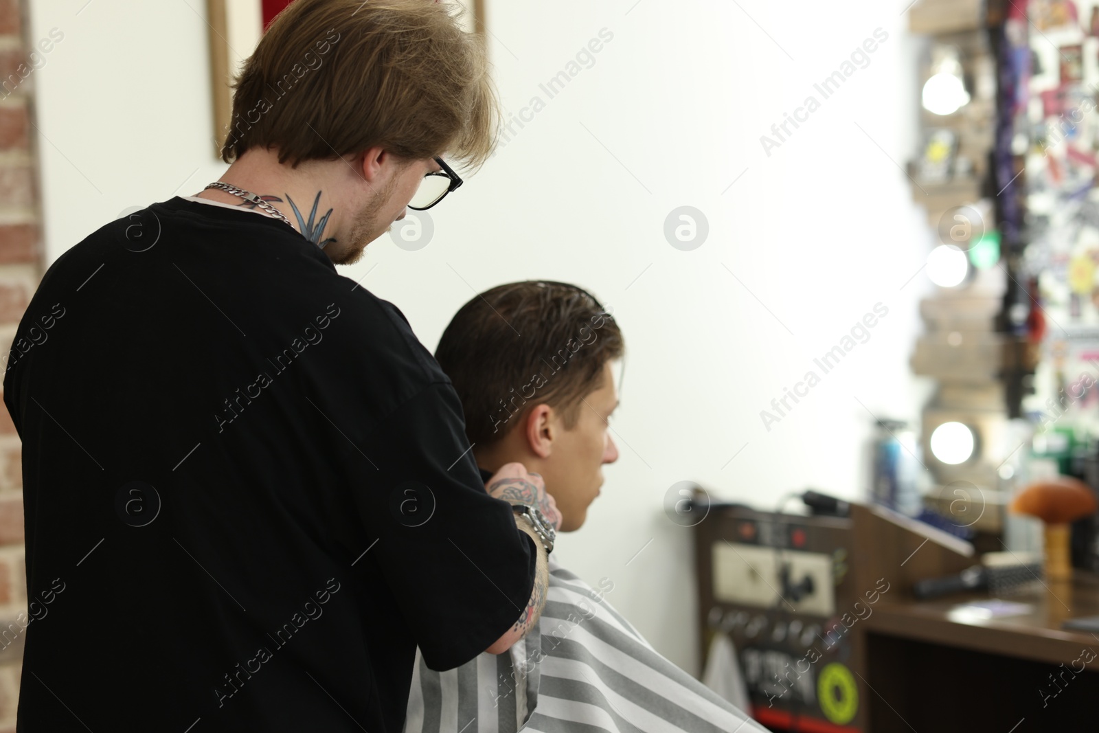 Professional barber working with client in barbershop, space for text Photo of Professional barber working with client in barbershop, space for text
