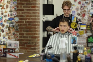 Photo of Professional barber working with client in barbershop