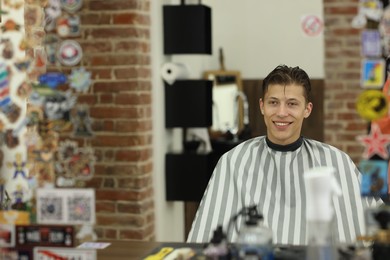 Photo of Hair cutting. Handsome man near mirror in barbershop