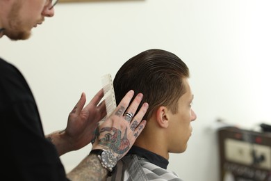 Photo of Professional barber working with client in barbershop, closeup