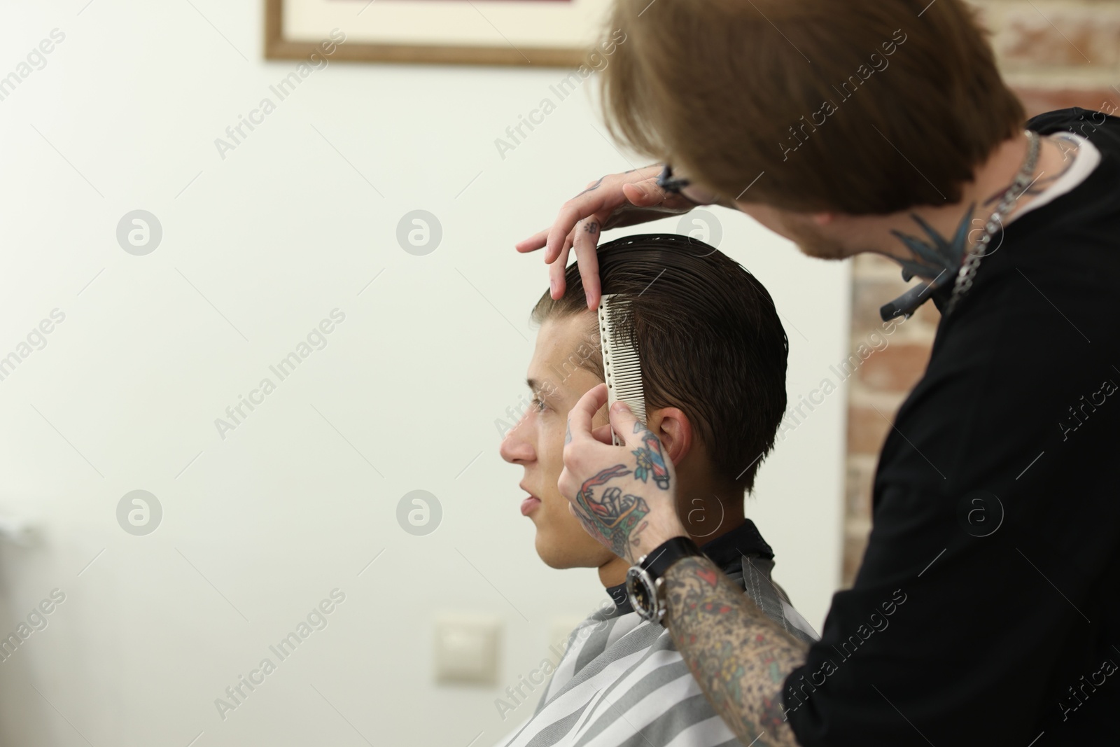 Professional barber working with client in barbershop, space for text Photo of Professional barber working with client in barbershop, space for text