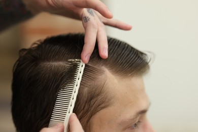Photo of Professional barber working with client in barbershop, closeup