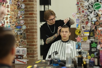 Photo of Professional barber working with client in barbershop