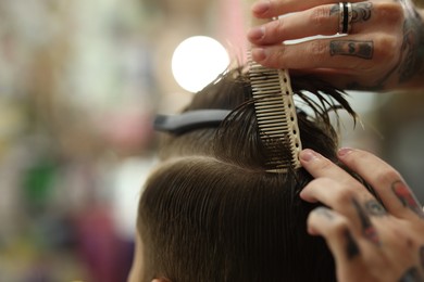 Photo of Professional barber working with client in barbershop, closeup. Space for text