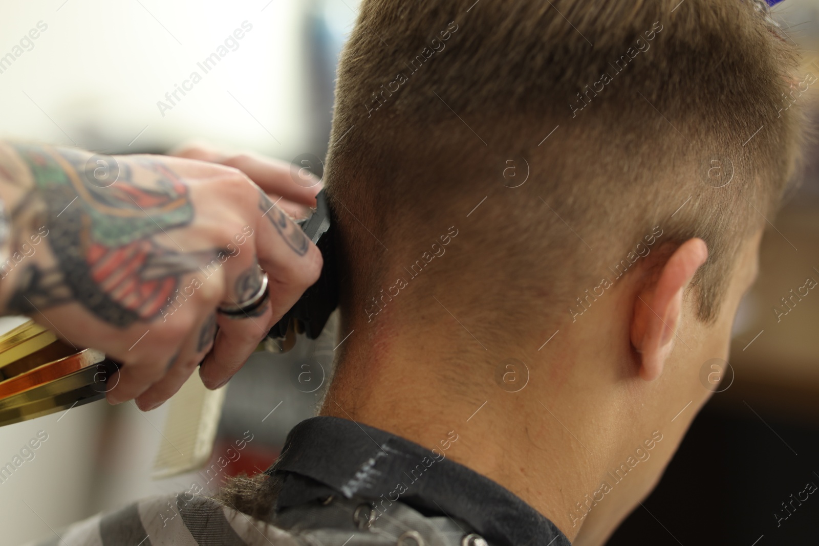 Photo of Professional barber making stylish haircut in barbershop, closeup