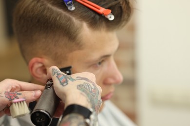 Photo of Professional barber making stylish haircut in barbershop, closeup