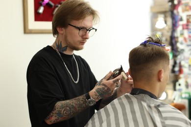 Photo of Professional barber making stylish haircut in barbershop