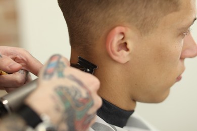 Photo of Professional barber making stylish haircut in barbershop, closeup