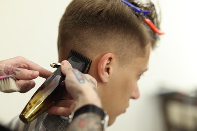 Photo of Professional barber making stylish haircut in barbershop, closeup