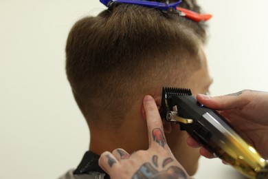 Photo of Professional barber making stylish haircut in barbershop, closeup