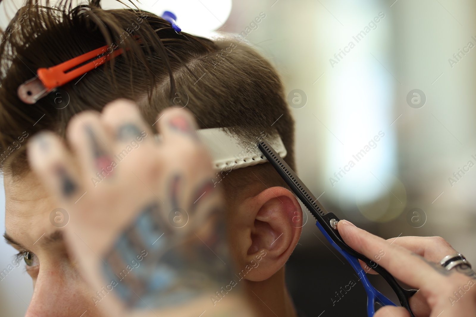 Professional barber cutting client's hair with scissors in barbershop, closeup Photo of Professional barber cutting client's hair with scissors in barbershop, closeup