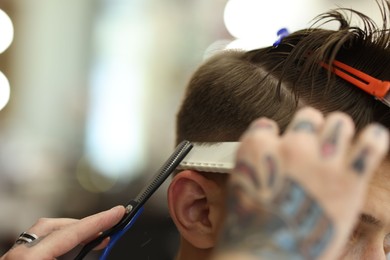 Photo of Professional barber cutting client's hair with scissors in barbershop, closeup. Space for text