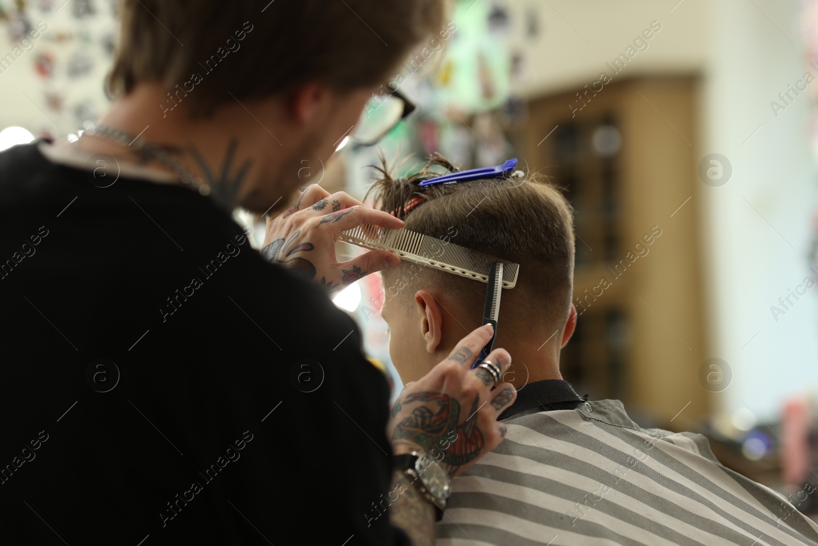 Professional barber cutting client's hair with scissors in barbershop, closeup Photo of Professional barber cutting client's hair with scissors in barbershop, closeup