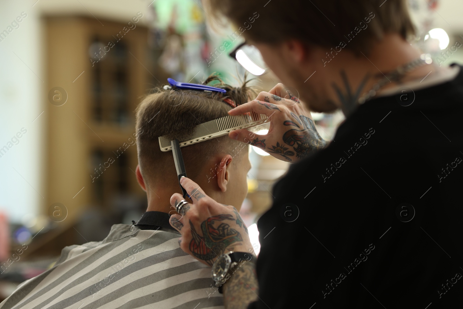 Professional barber cutting client's hair with scissors in barbershop, closeup Photo of Professional barber cutting client's hair with scissors in barbershop, closeup