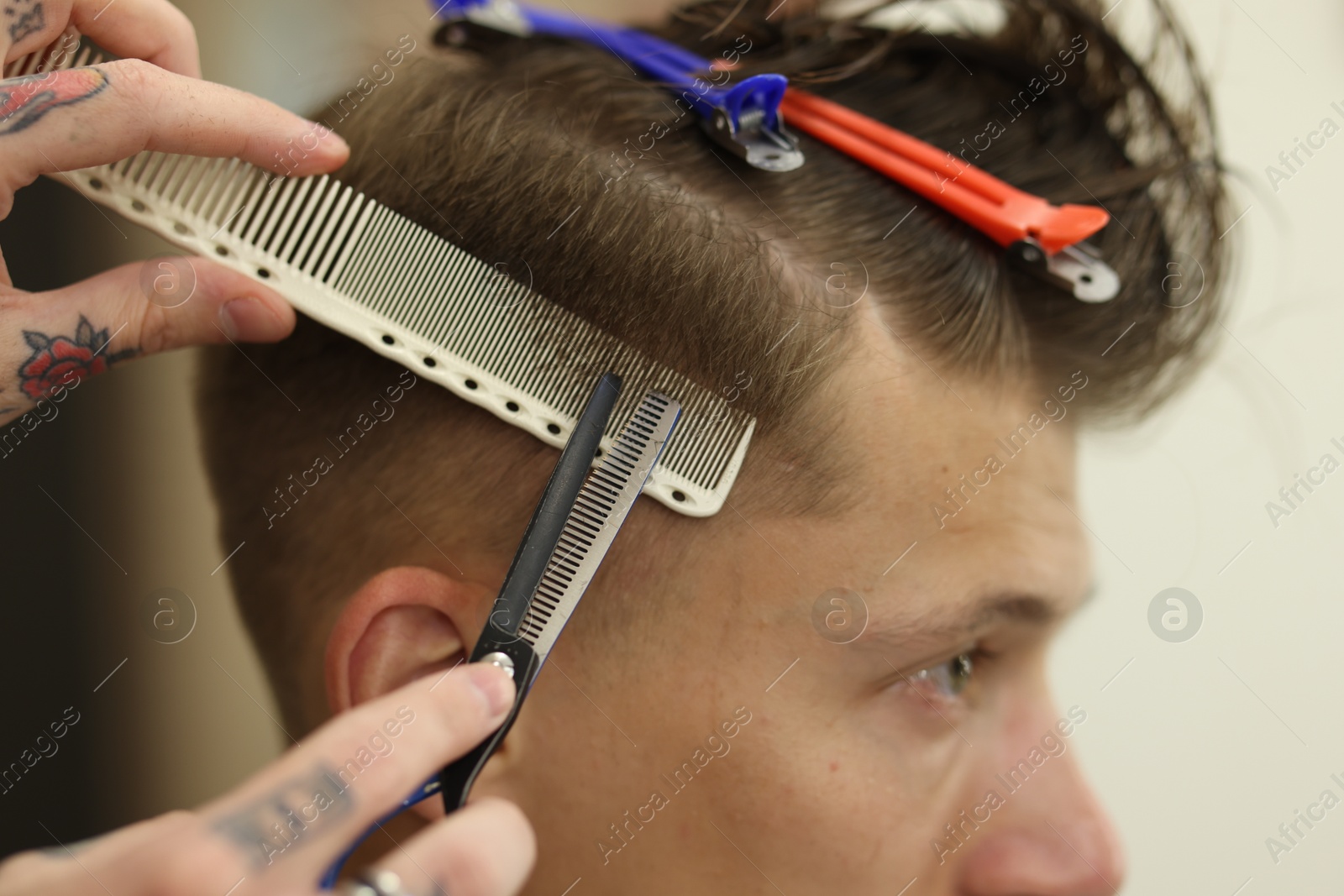 Professional barber cutting client's hair with scissors in barbershop, closeup Photo of Professional barber cutting client's hair with scissors in barbershop, closeup
