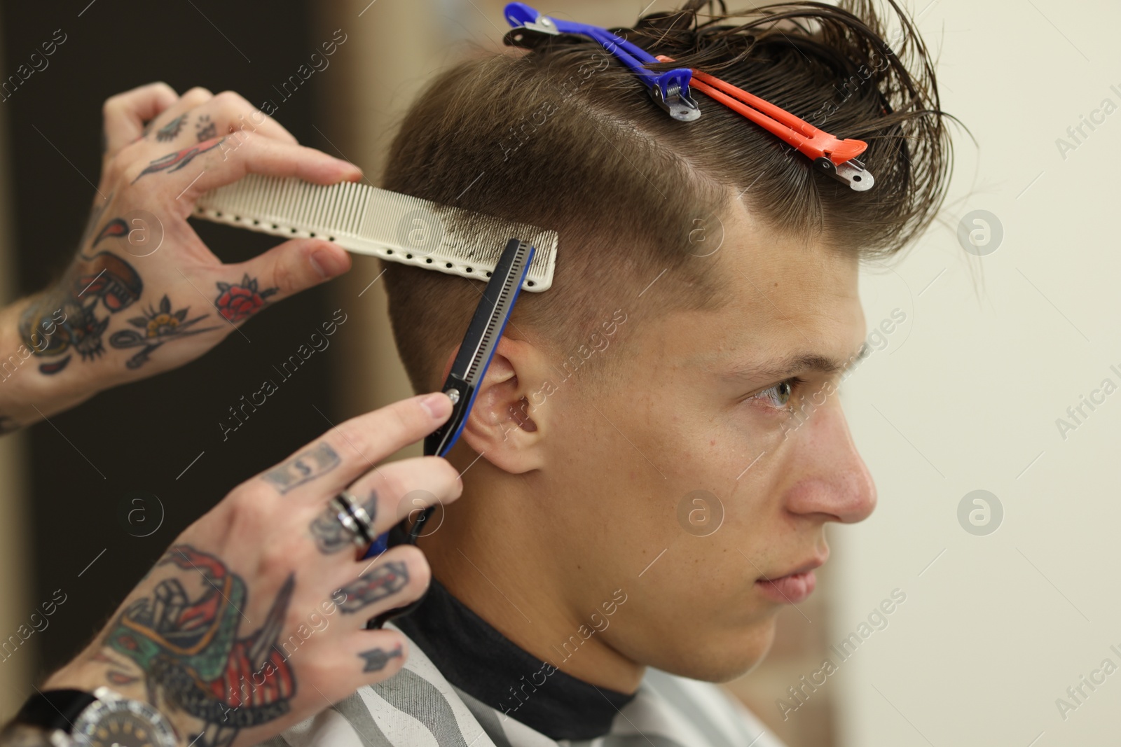 Professional barber cutting client's hair with scissors in barbershop, closeup Photo of Professional barber cutting client's hair with scissors in barbershop, closeup