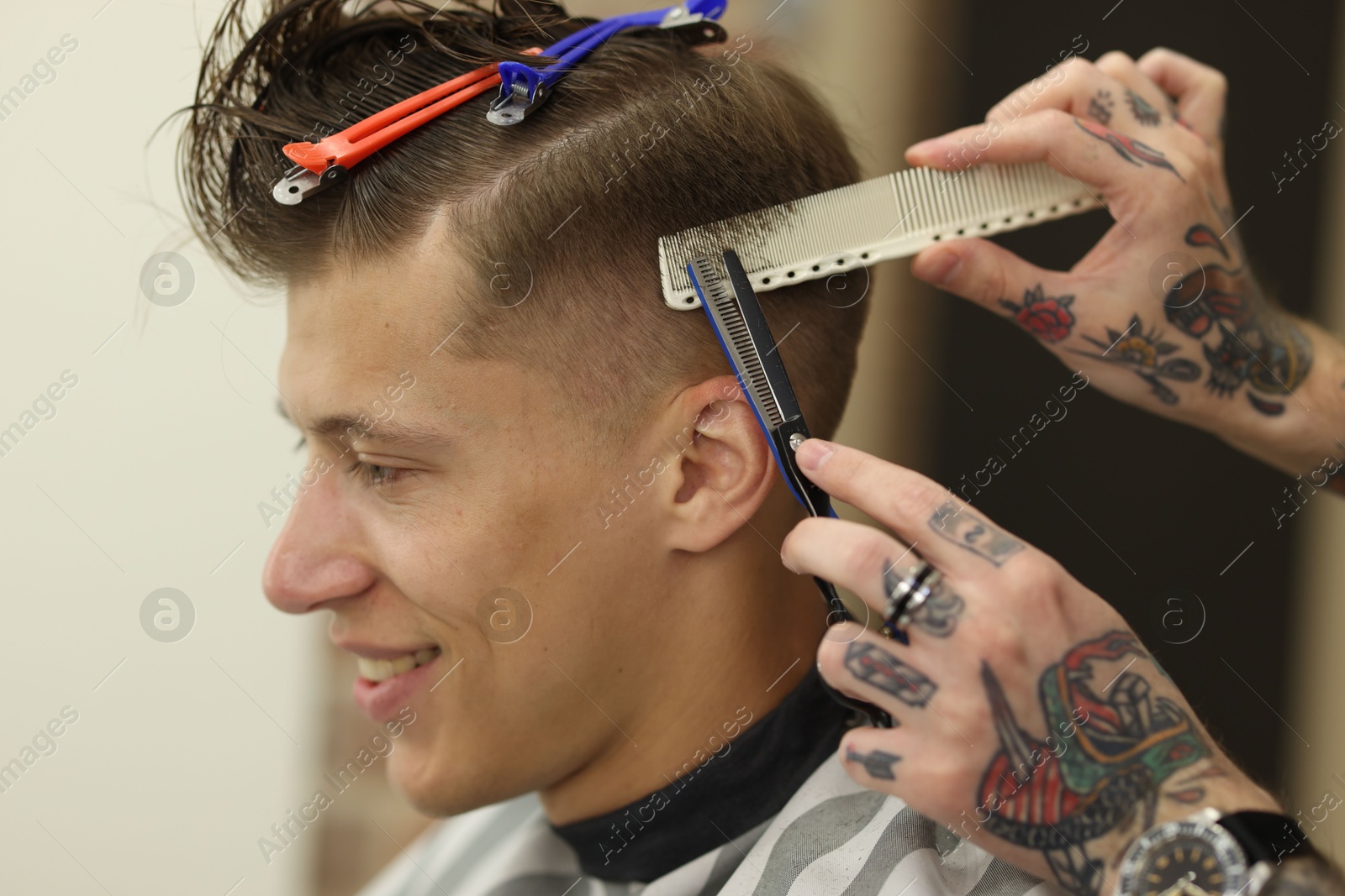 Professional barber cutting client's hair with scissors in barbershop, closeup Photo of Professional barber cutting client's hair with scissors in barbershop, closeup