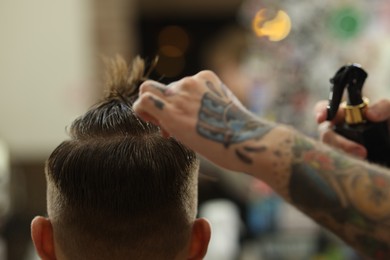 Photo of Professional barber making stylish haircut in barbershop, closeup