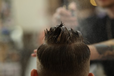 Photo of Professional barber making stylish haircut in barbershop, closeup