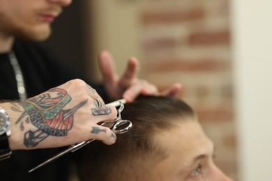 Photo of Professional barber making stylish haircut in barbershop, closeup