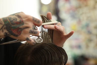 Photo of Professional barber making stylish haircut in barbershop, closeup