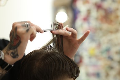 Photo of Professional barber cutting client's hair with scissors in barbershop, closeup. Space for text