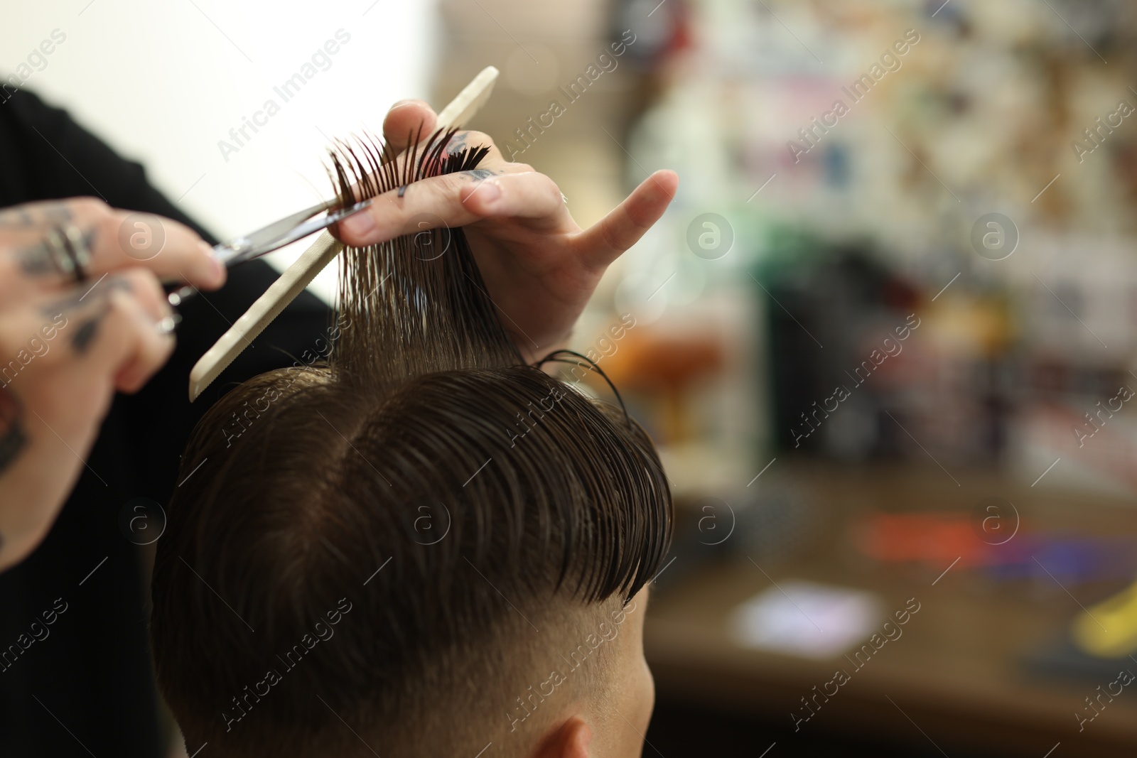 Professional barber cutting client's hair with scissors in barbershop, closeup. Space for text Photo of Professional barber cutting client's hair with scissors in barbershop, closeup. Space for text