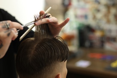 Photo of Professional barber cutting client's hair with scissors in barbershop, closeup. Space for text