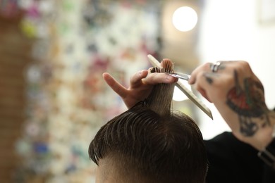 Photo of Professional barber cutting client's hair with scissors in barbershop, closeup. Space for text