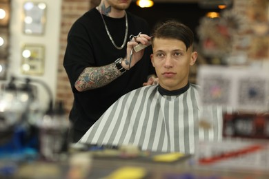 Photo of Professional barber making stylish haircut in barbershop