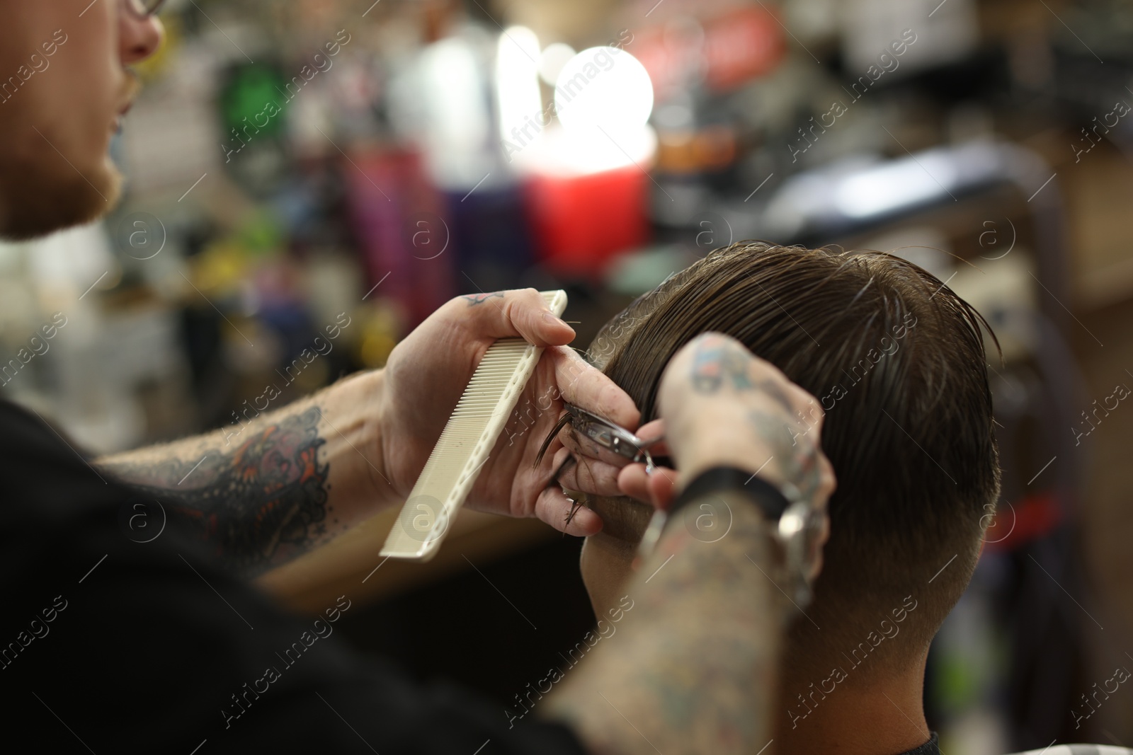 Professional barber cutting client's hair with scissors in barbershop, closeup Photo of Professional barber cutting client's hair with scissors in barbershop, closeup