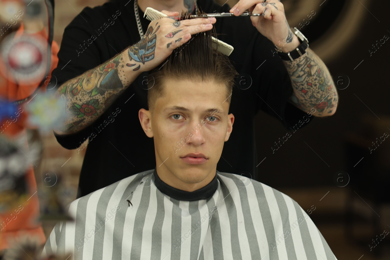 Professional barber cutting client's hair with scissors in barbershop, closeup Photo of Professional barber cutting client's hair with scissors in barbershop, closeup