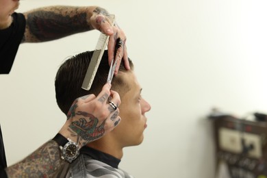 Photo of Professional barber cutting client's hair with scissors in barbershop, closeup. Space for text