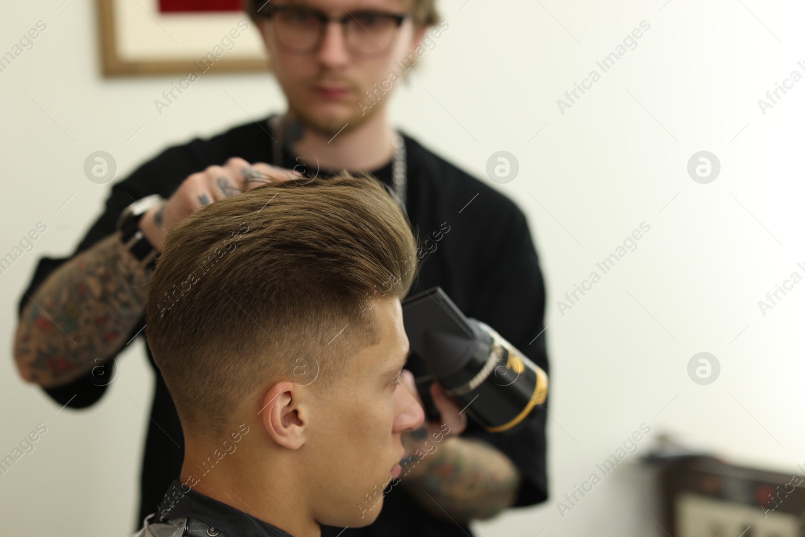Professional barber blow drying client's hair in barbershop, selective focus. Space for text Photo of Professional barber blow drying client's hair in barbershop, selective focus. Space for text