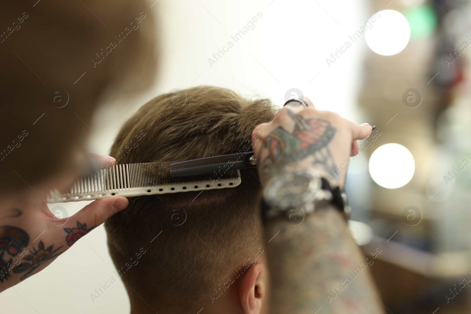 Professional barber cutting client's hair with scissors in barbershop, closeup Photo of Professional barber cutting client's hair with scissors in barbershop, closeup