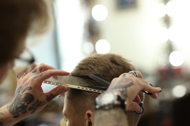 Photo of Professional barber cutting client's hair with scissors in barbershop, closeup