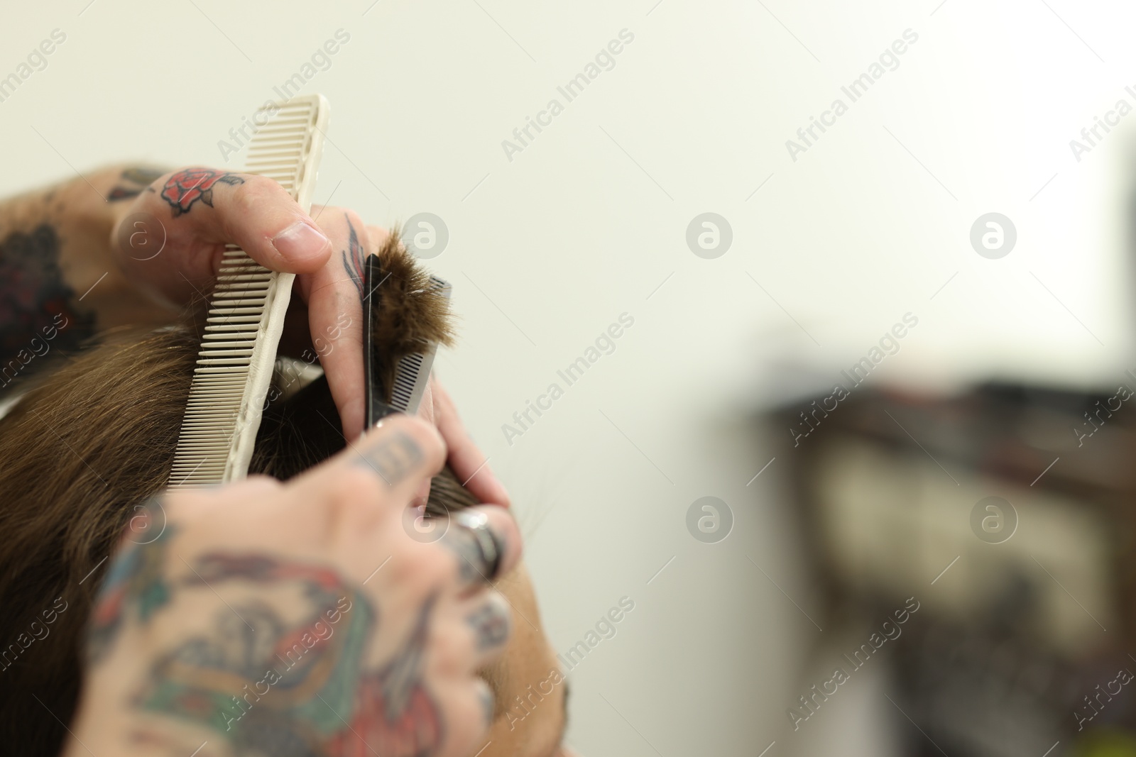 Professional barber cutting client's hair with scissors in barbershop, closeup. Space for text Photo of Professional barber cutting client's hair with scissors in barbershop, closeup. Space for text