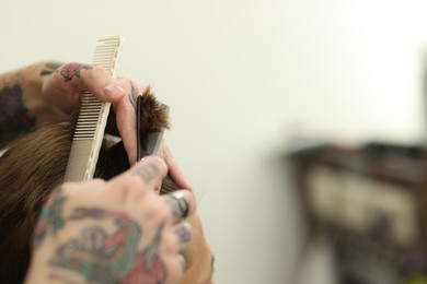 Photo of Professional barber cutting client's hair with scissors in barbershop, closeup. Space for text