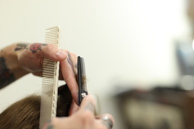 Photo of Professional barber cutting client's hair with scissors in barbershop, closeup. Space for text