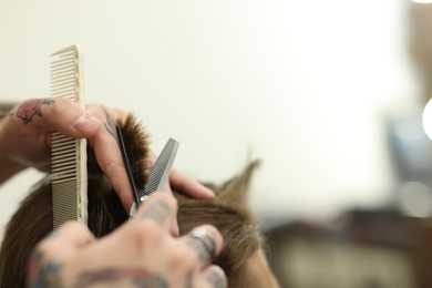Photo of Professional barber cutting client's hair with scissors in barbershop, closeup. Space for text