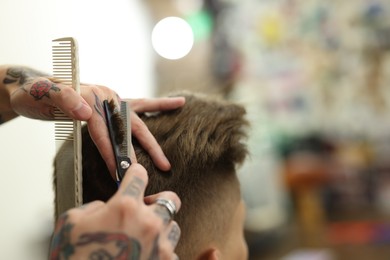 Photo of Professional barber cutting client's hair with scissors in barbershop, closeup. Space for text