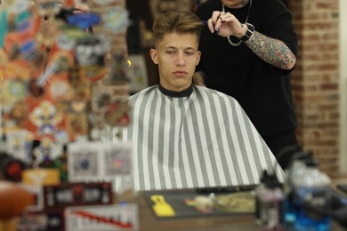 Photo of Professional barber cutting client's hair with scissors in barbershop, closeup