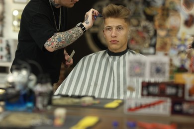 Photo of Professional barber cutting client's hair with scissors in barbershop, closeup