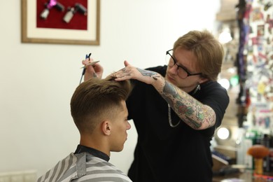 Photo of Professional barber making stylish haircut in barbershop