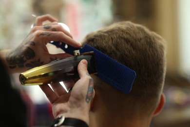 Photo of Professional barber making stylish haircut in barbershop, closeup