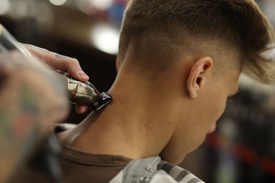 Photo of Professional barber making stylish haircut in barbershop, closeup
