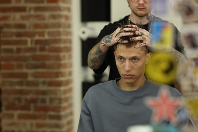Photo of Professional barber working with client in barbershop, closeup. Space for text