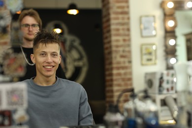 Photo of Professional barber working with client in barbershop, selective focus. Space for text