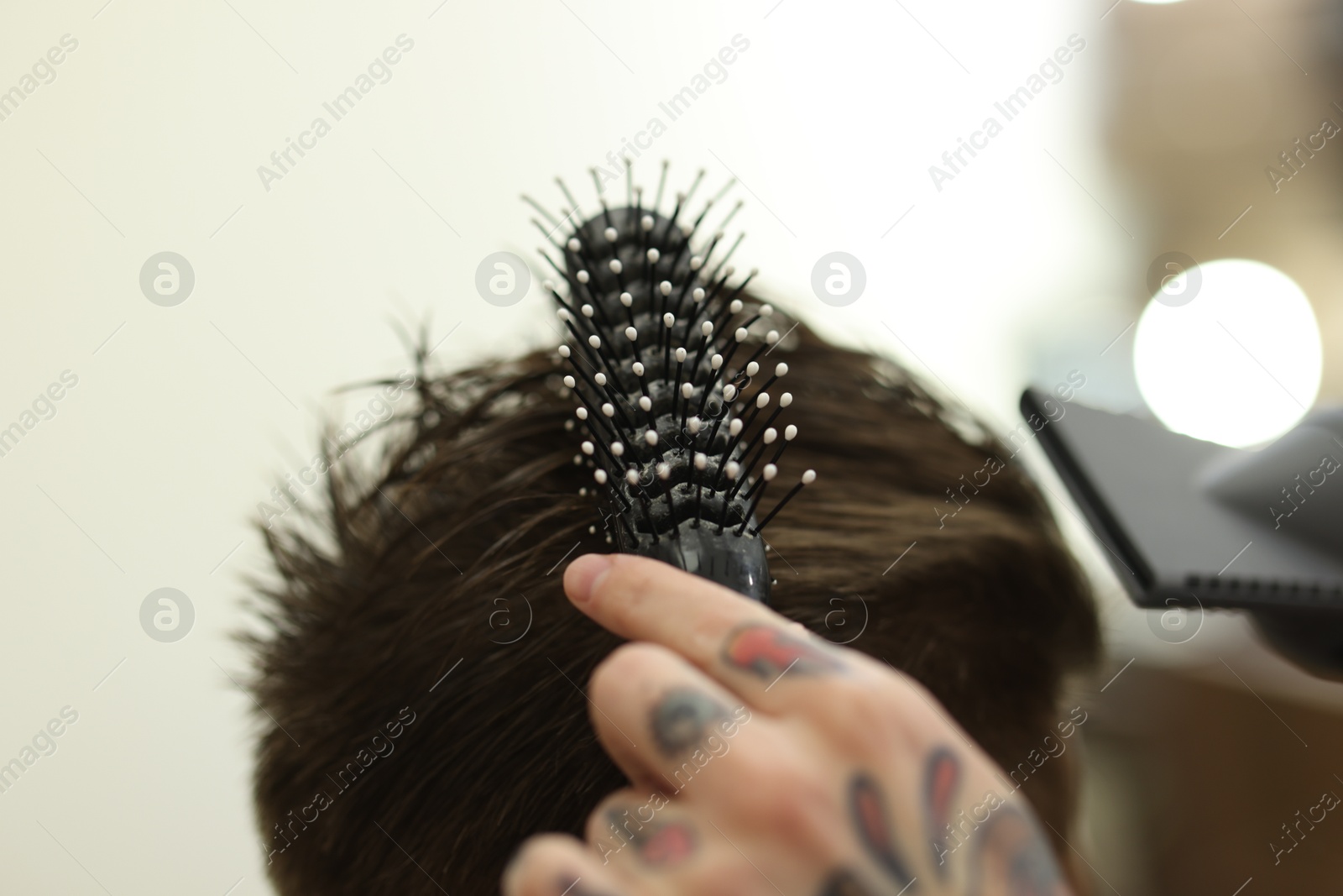 Professional barber blow drying client's hair in barbershop, closeup Photo of Professional barber blow drying client's hair in barbershop, closeup