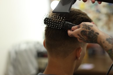 Photo of Professional barber blow drying client's hair in barbershop, closeup. Space for text